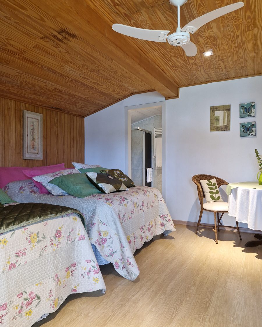 Suíte Verde - cama com almofadas e vista para o banheiro